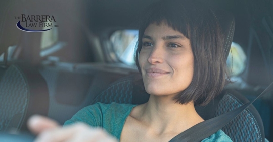 Woman in a car driving with a smile on her face.